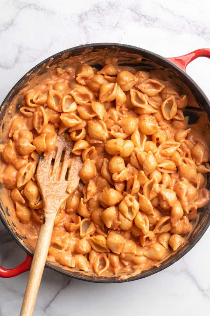 Stirring vegan creamy tomato pasta in skillet