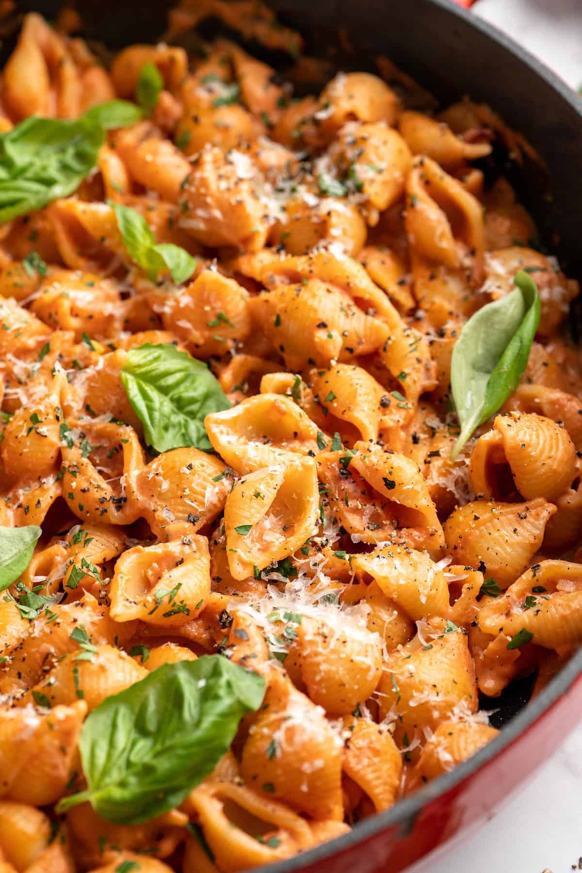 Skillet of creamy tomato pasta with fresh basil leaves