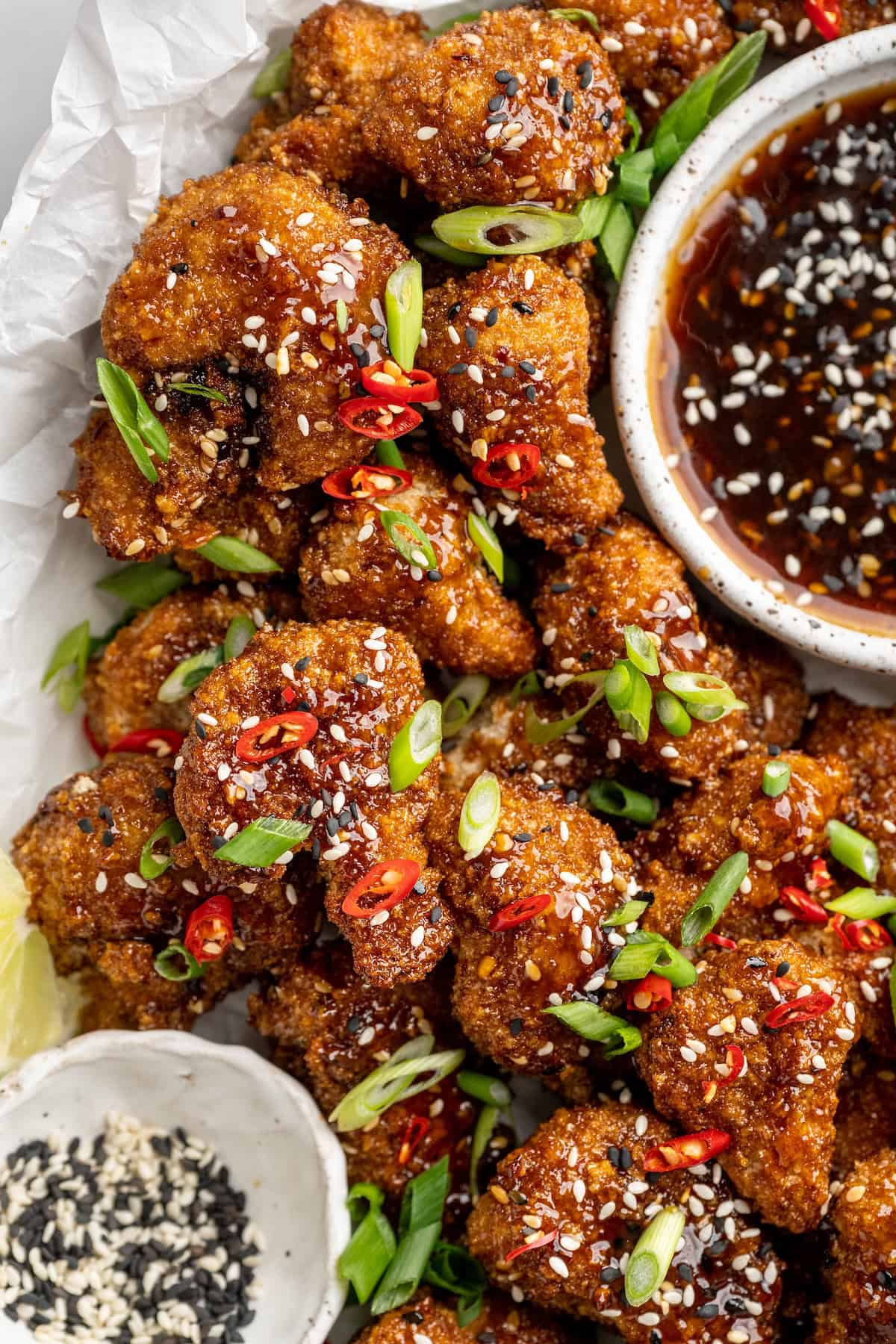 General Tso cauliflower tastes just like the takeout version! Crispy on the outside and coated in a sweet, sticky and spicy sauce. Yum! Platter of General Tso cauliflower with bowl of sauce