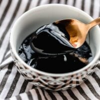 A bowl of balsamic glaze with a spoon over it.