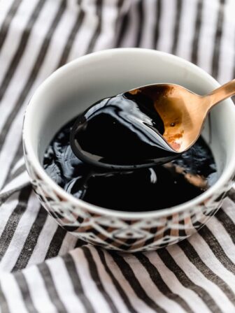 A bowl of balsamic glaze with a spoon over it.