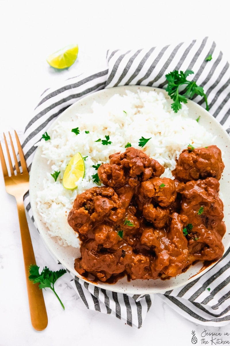 Indian butter cauliflower in a plate with white rice and limes.