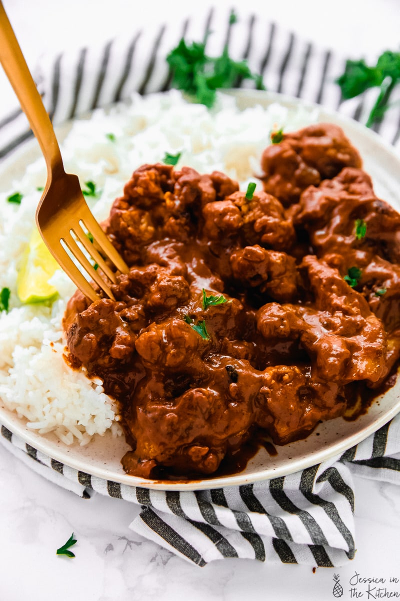 A fork digging into indian butter cauliflower.