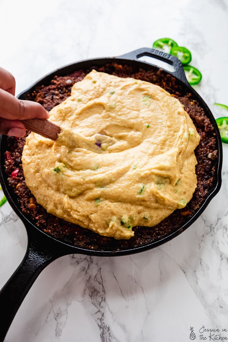 Stirring cornbread batter in a skillet. 