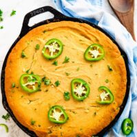 Cornbread casserole in a skillet, topped with sliced jalapeno.