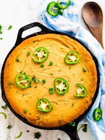 Cornbread casserole in a skillet, topped with sliced jalapeno.
