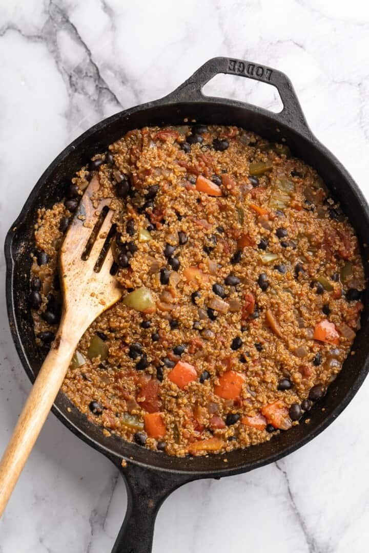 This vegan chili cornbread casserole is one of the BEST casseroles ever! The secret? Sweet, crispy cornbread baked on top of delicious chili. Chili in skillet with wooden spoon