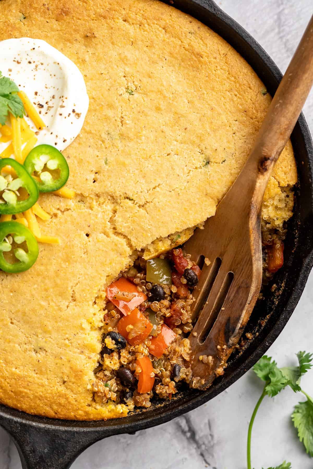 This vegan chili cornbread casserole is one of the BEST casseroles ever! The secret? Sweet, crispy cornbread baked on top of delicious chili. Wooden spoon digging into chili cornbread casserole