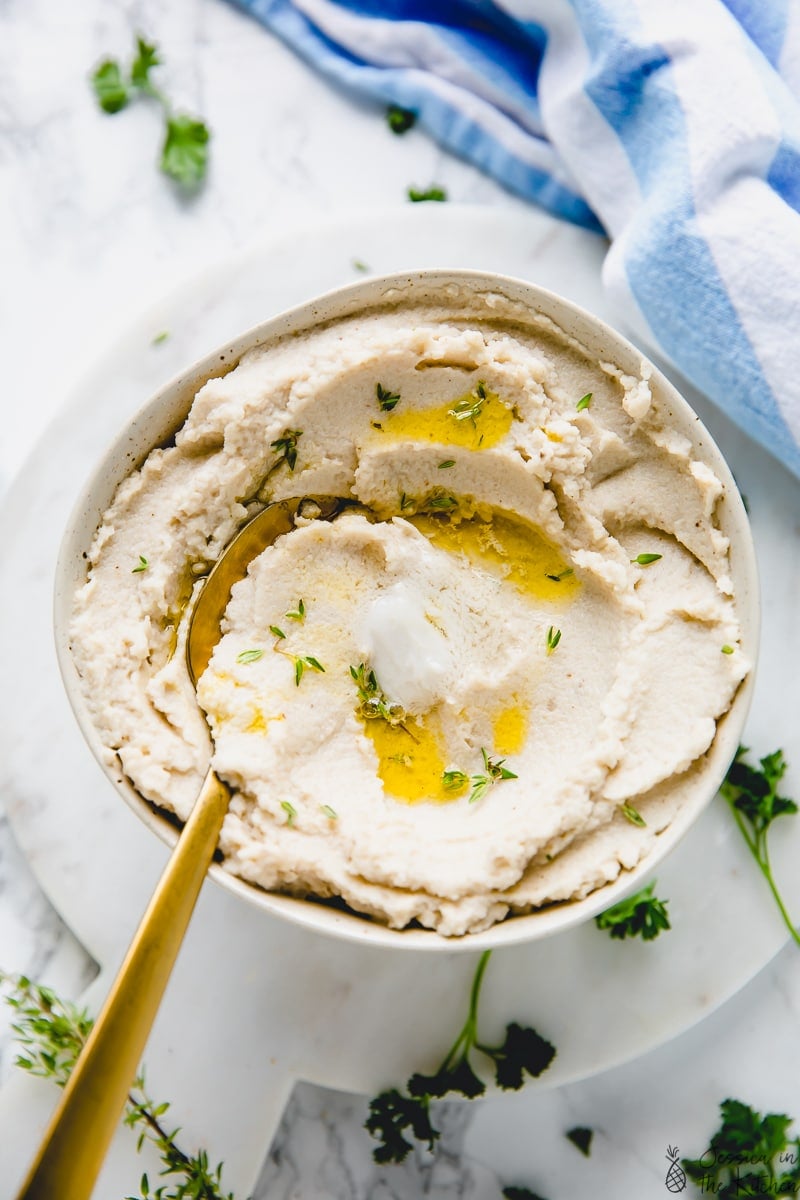 Top down view of mashed cauliflower in a bowl with a spoon. 