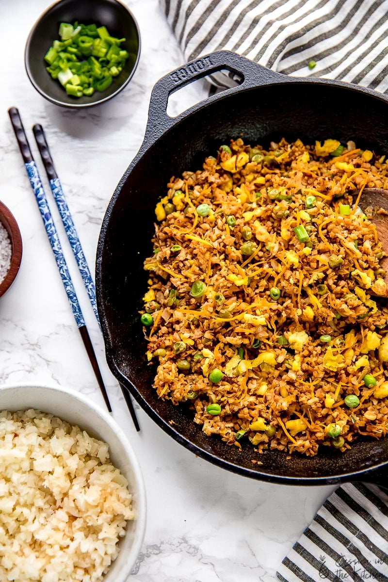 Top down view of vegan fried rice in a black skillet with chopsticks on the side. 