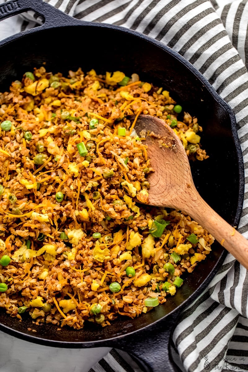 Top down shot of a wood spoon stirring vegan fried rice. 