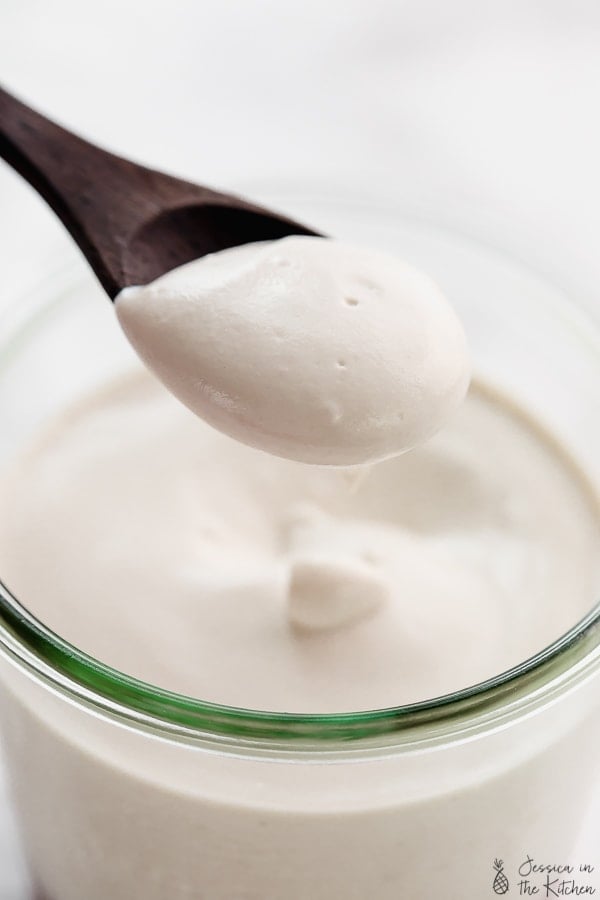 Spoonful of vegan yogurt held over jar