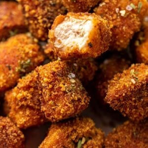 Closeup of vegan tofu nuggets, one with a bite taken out.
