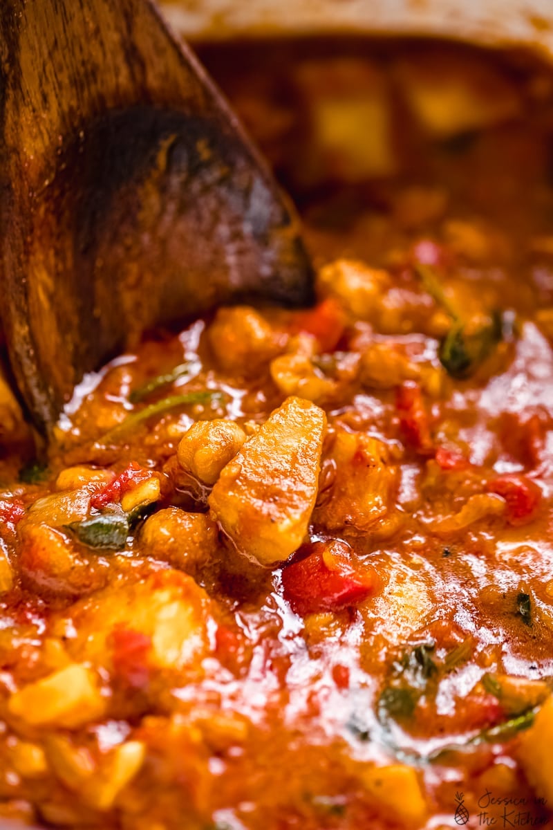 Close up of wooden spoon stirring sweet potato curry. 