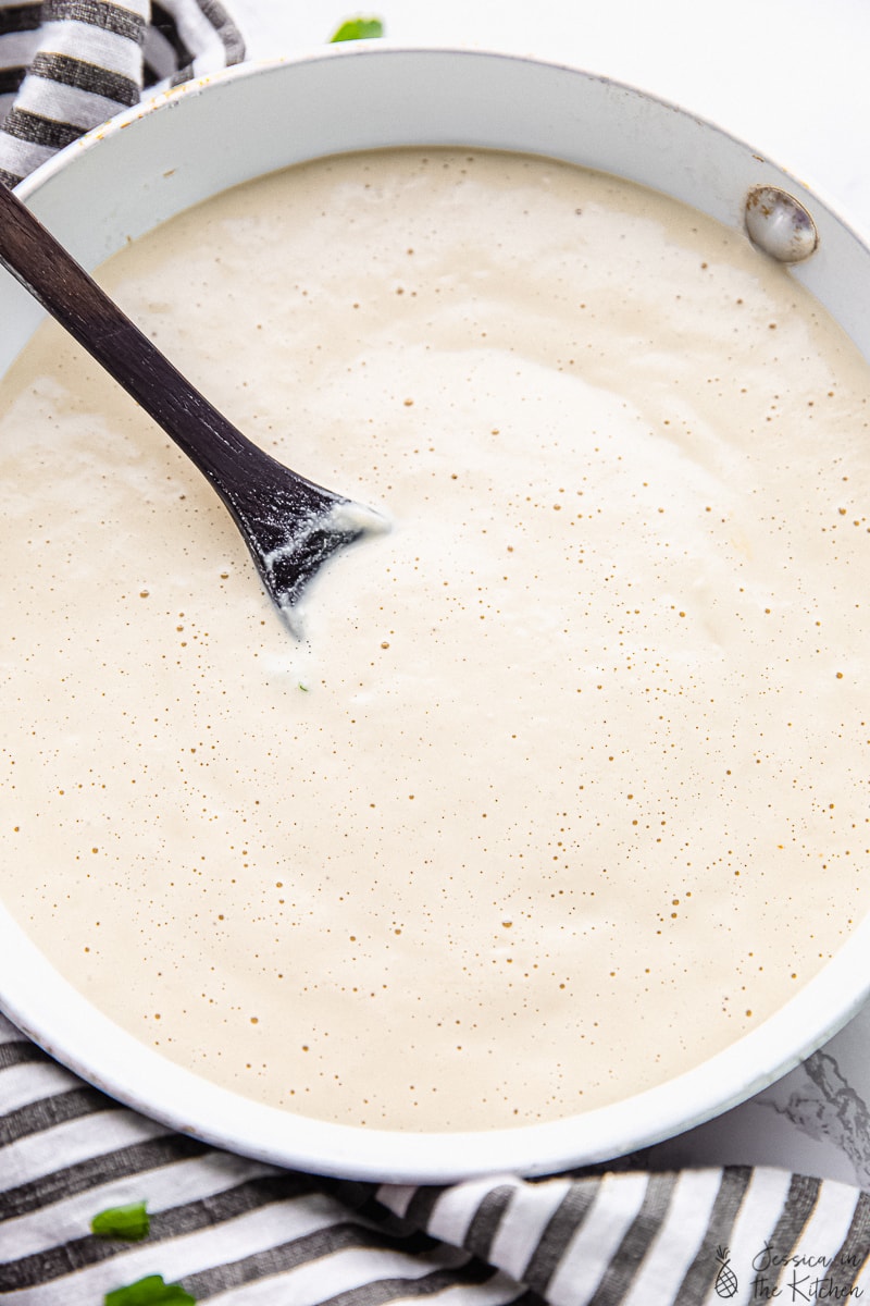 Overhead shot of vegan alfredo sauce in a bowl with a spoon in it.