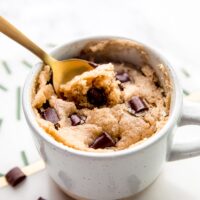 A gold spoon scooping into a vegan chocolate chip mug cake.