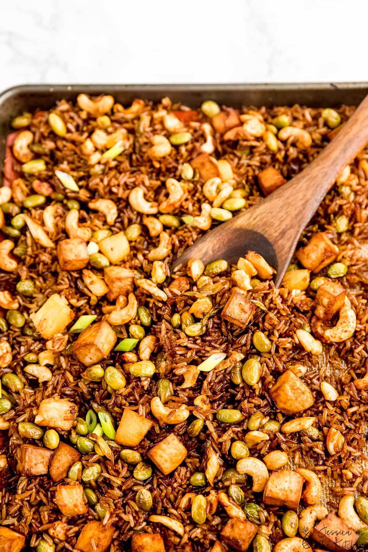 Overhead view of sheet pan fried rice being stirred in a sheet pan.