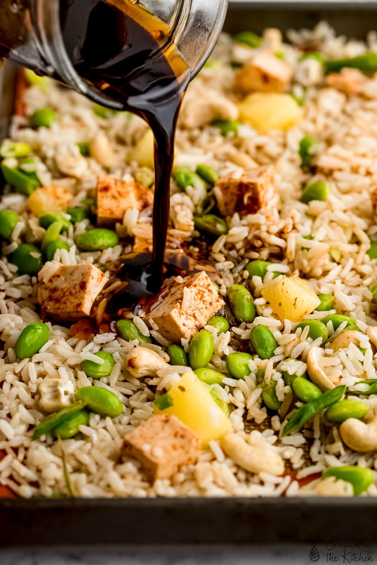 Pouring sauce onto pan of rice for fried rice