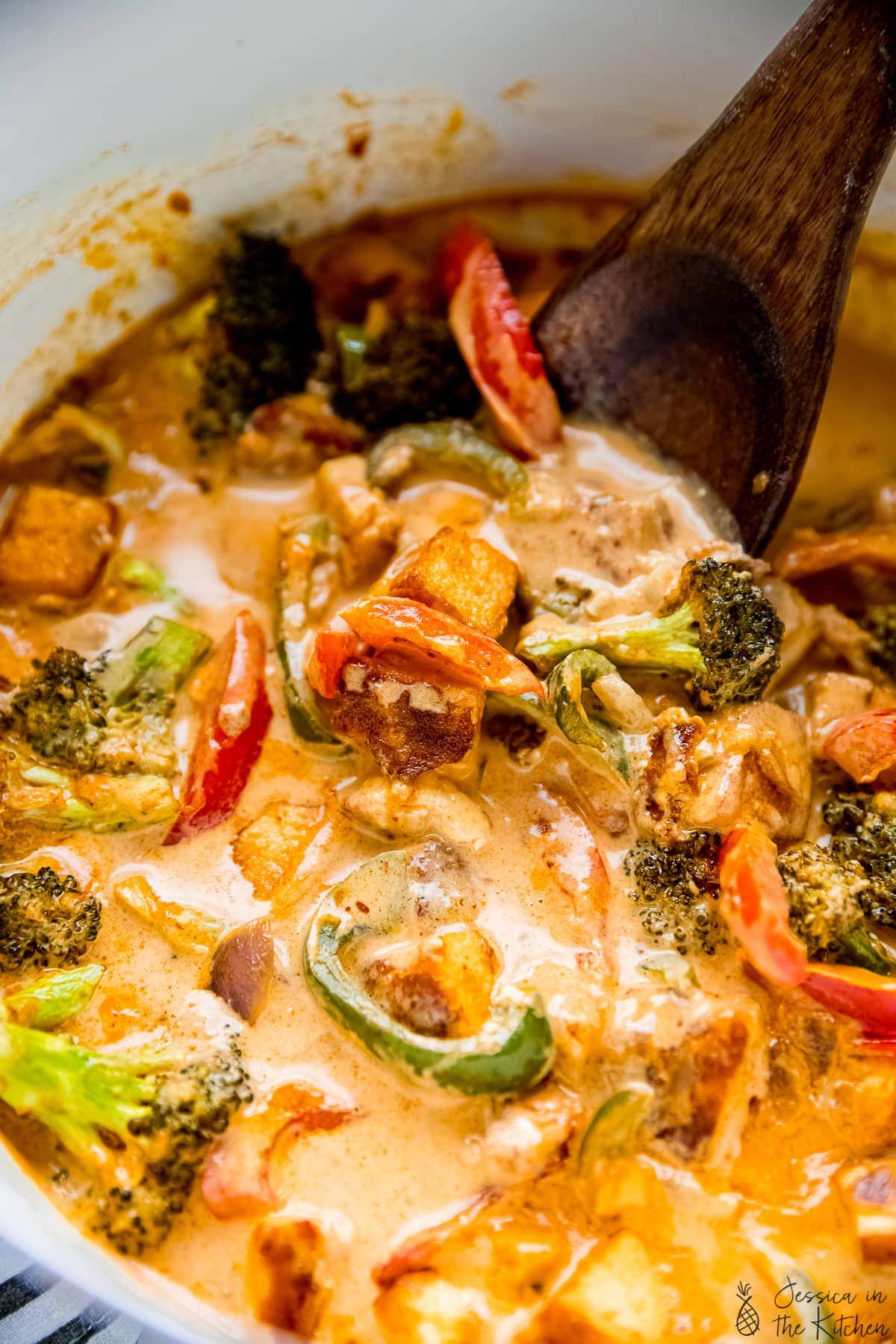 Wooden spoon stirring Thai red curry