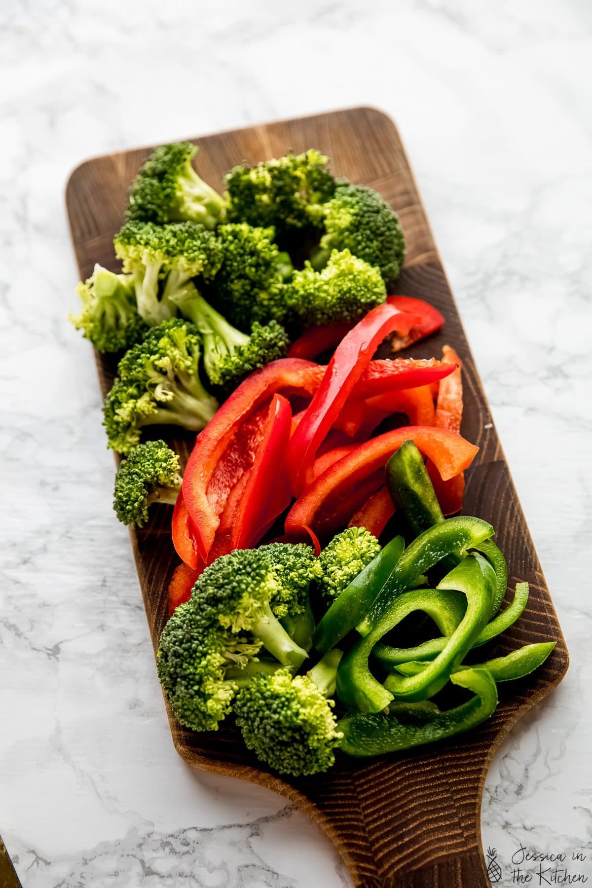 Chopped broccoli and bell peppers on a cutting board.