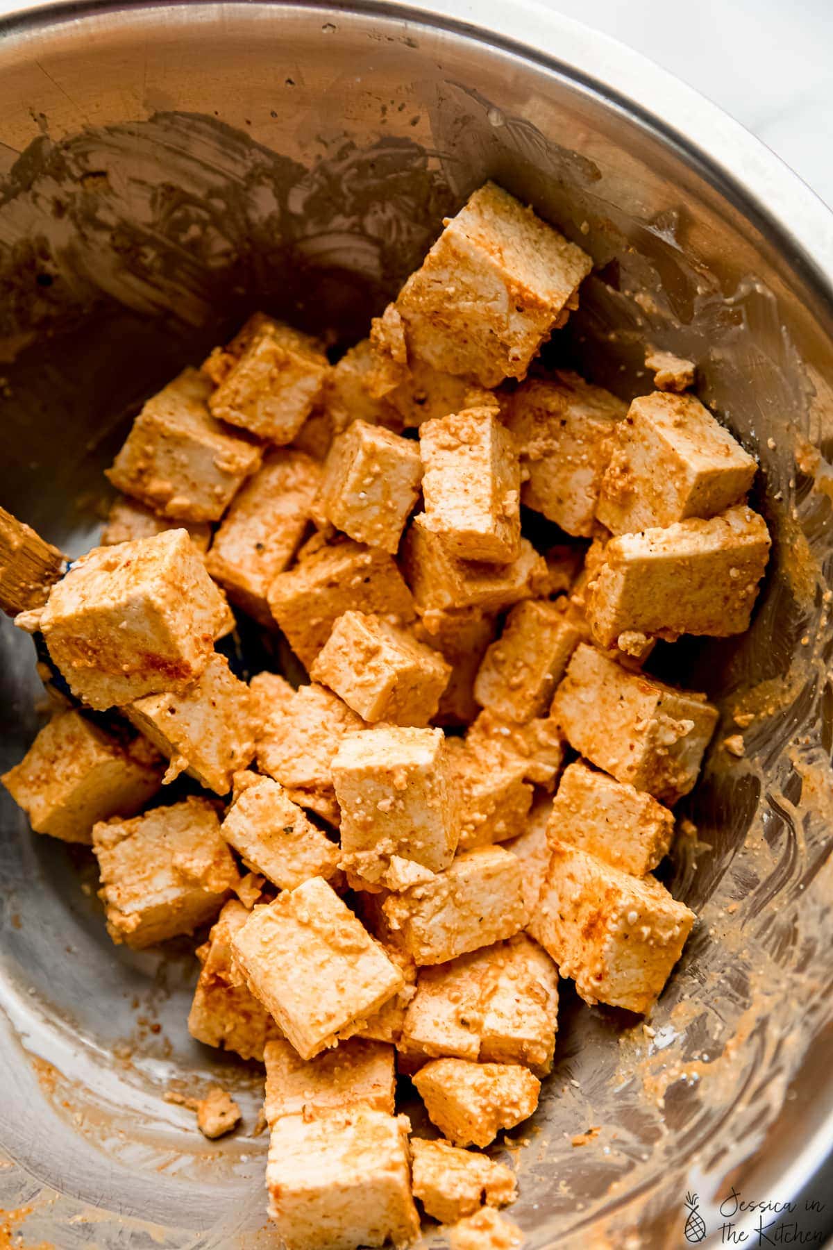Tofu cubes in metal bowl with marinade