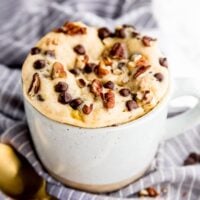 Banana bread mug cake in a mug with a golden spoon in front.