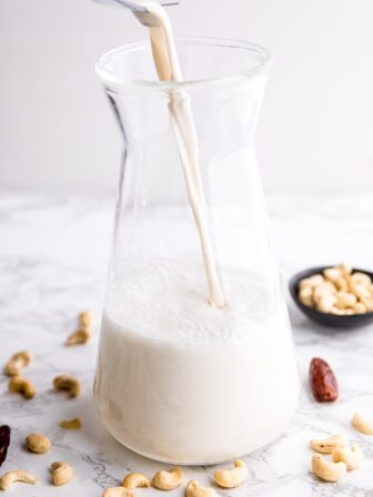 Cashew milk being poured into a glass jug.