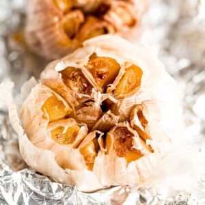 Overhead view of two roasted garlic bulbs on foil.
