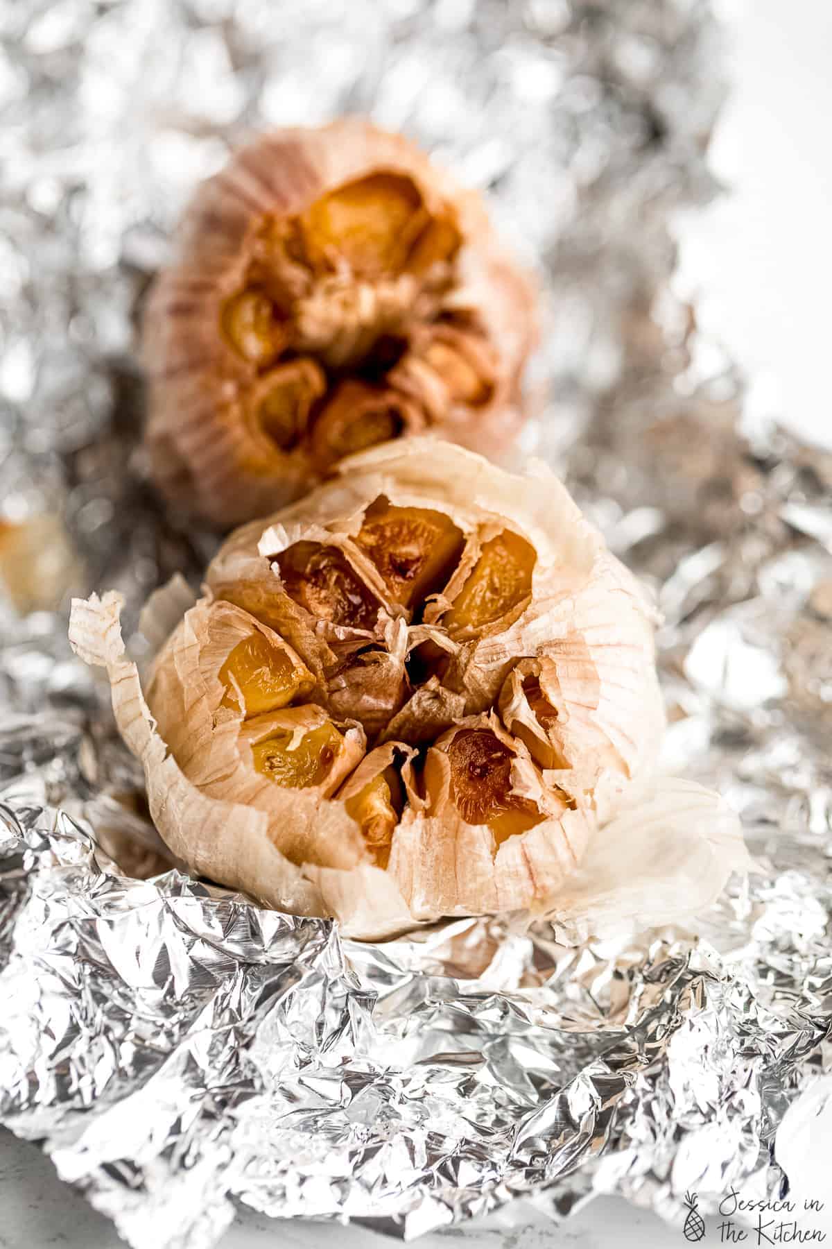 Two heads of roasted garlic on foil