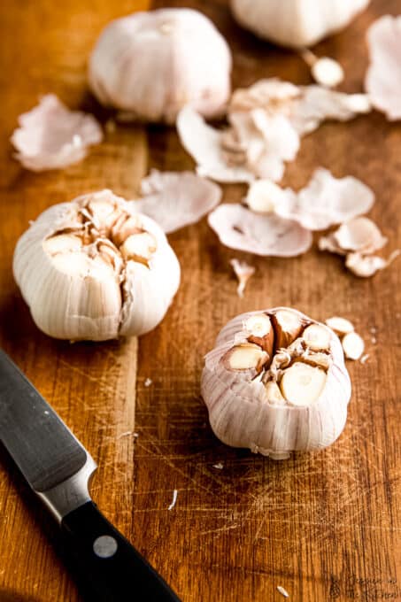 Two garlic heads with tops cut off, exposing cloves