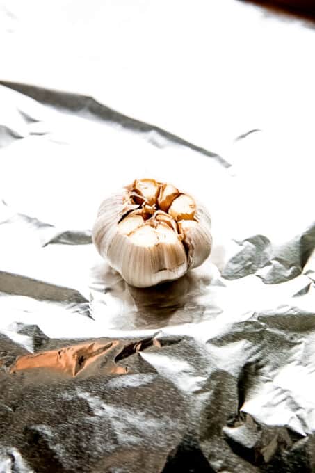 Head of garlic with top removed on sheet of foil