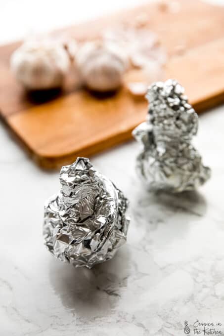 Two garlic heads wrapped tightly with foil