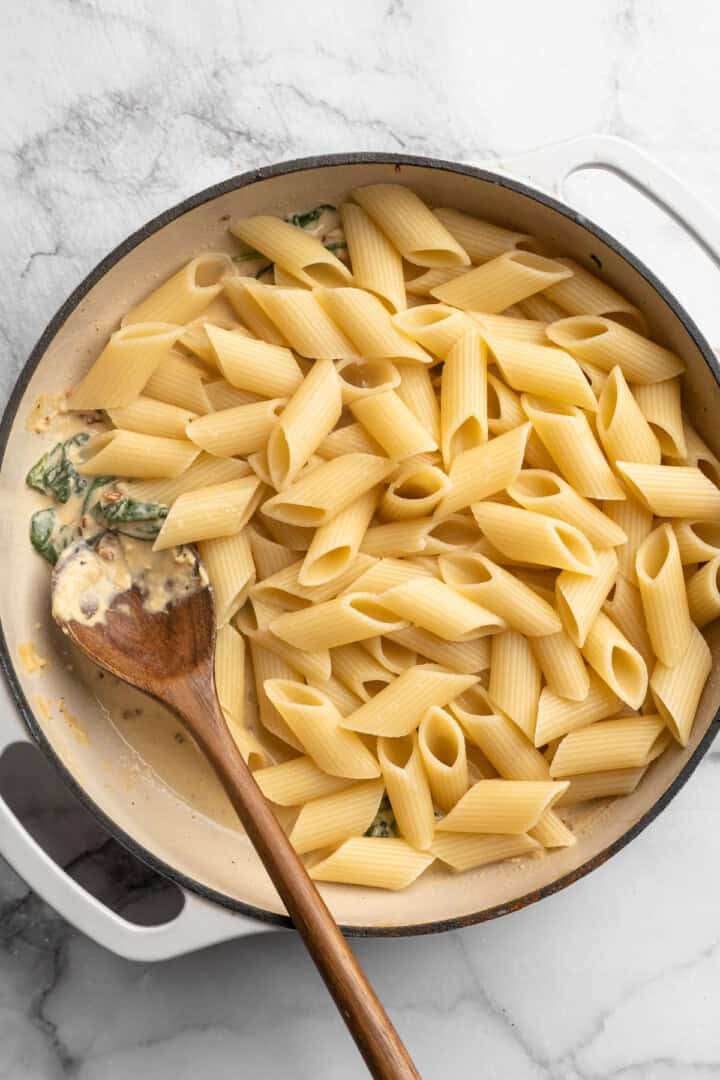 Pasta added to Dutch oven with hummus sauce.