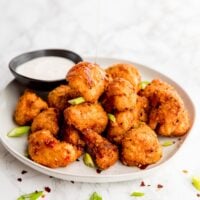 Bang bang cauliflower wings on a plate with dip on the side.