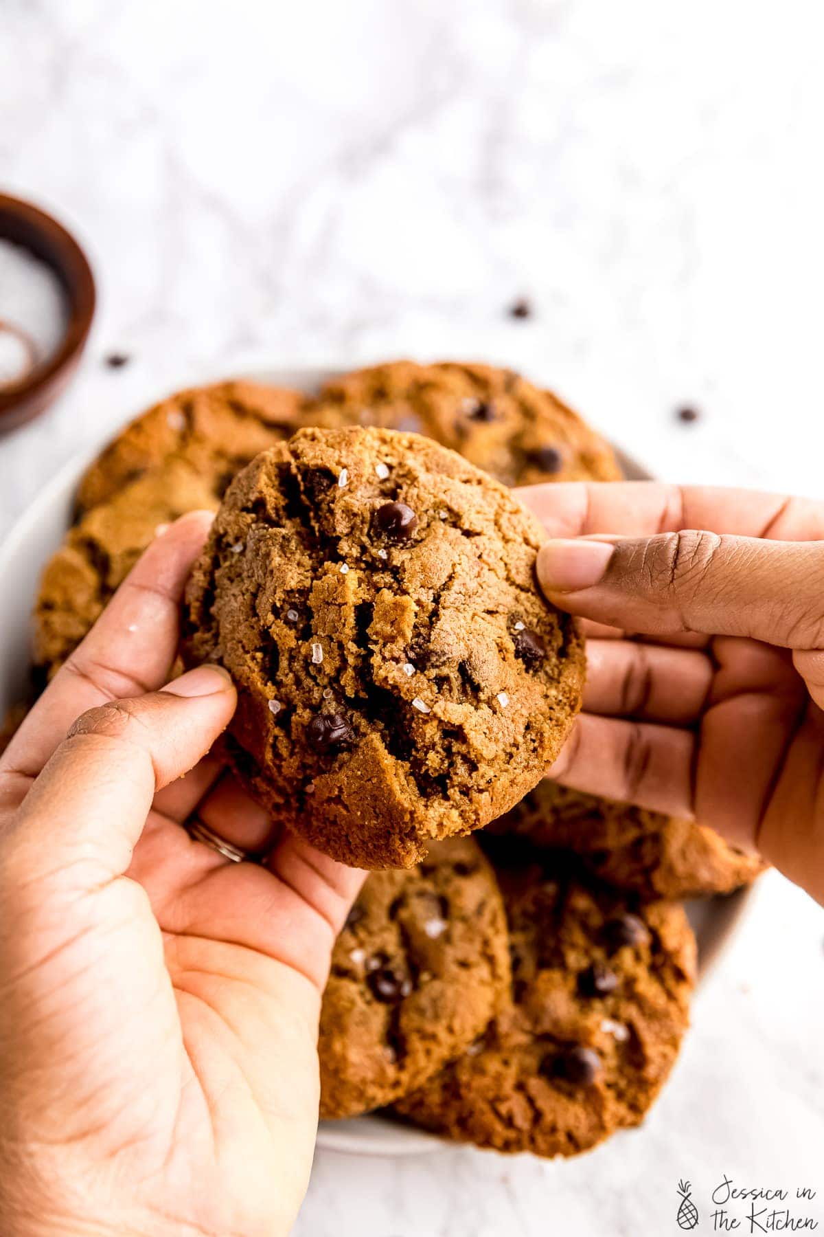 Hand breaking 5 ingredient chocolate chip cookies in half.