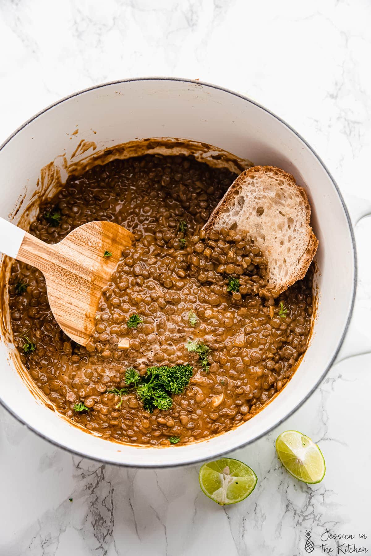 Top down view of vegan lentil stew in a pot with a slice of bread.