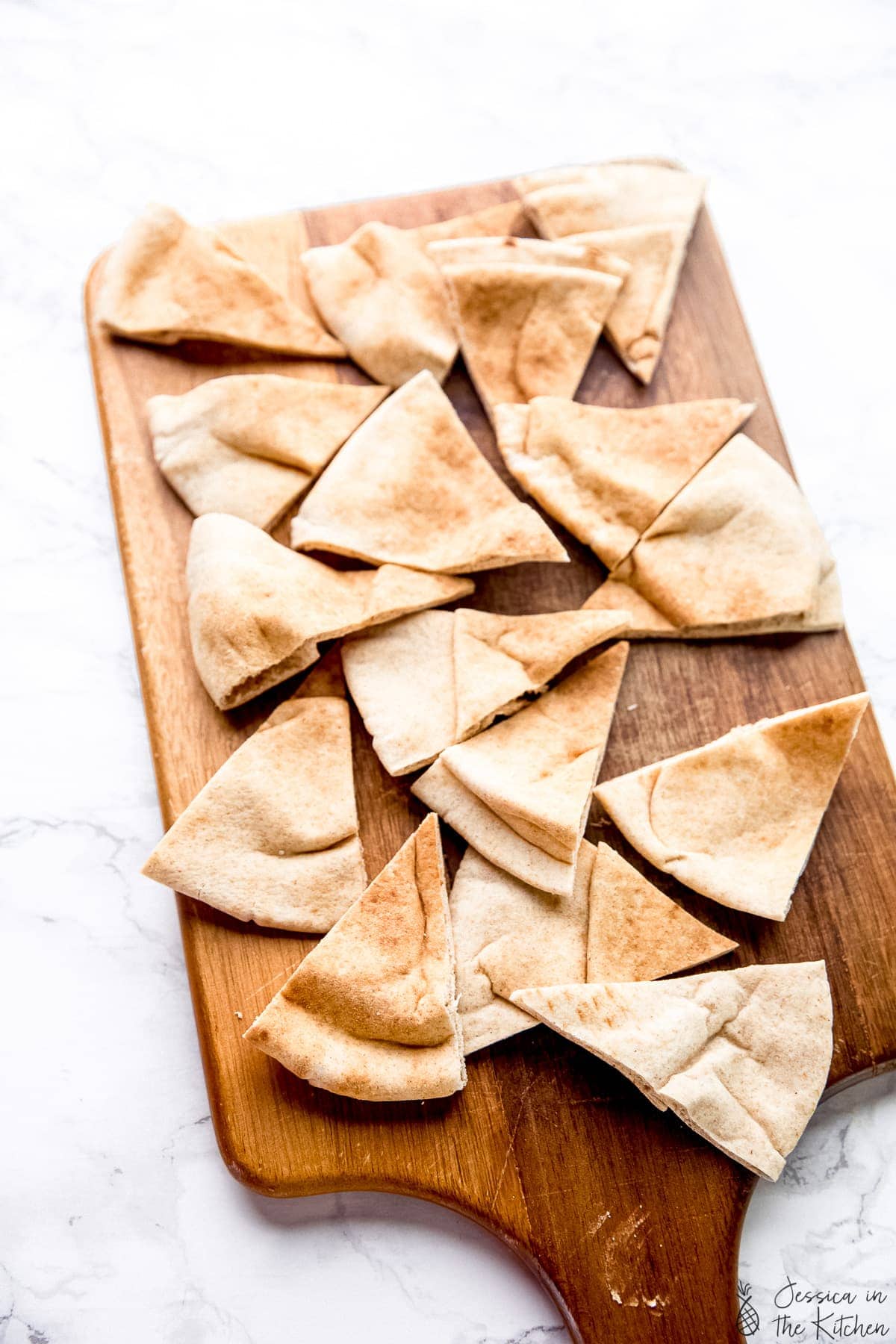 Sliced pita chips on a cutting board.