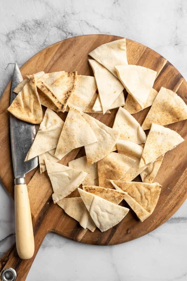 Pita wedges on cutting board with knife.