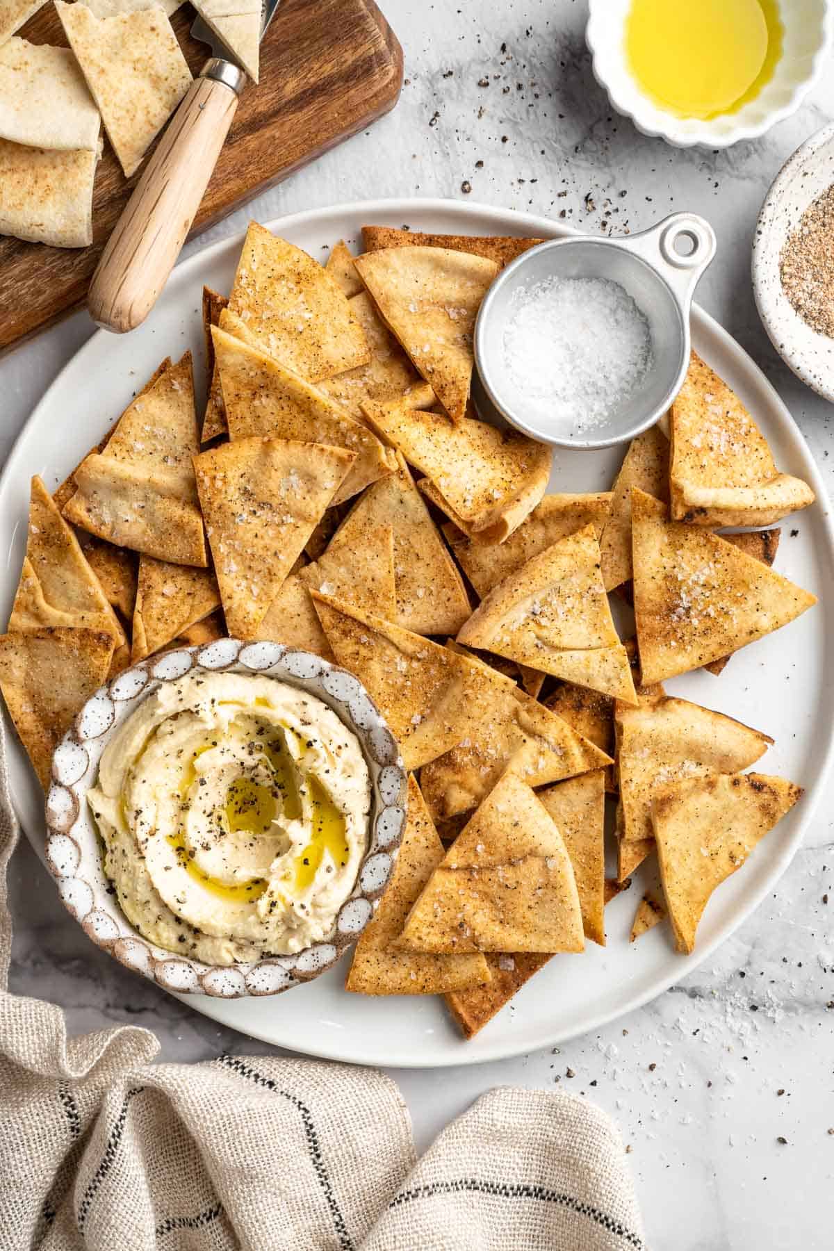 Platter with homemade pita chips and bowls of salt and hummus.