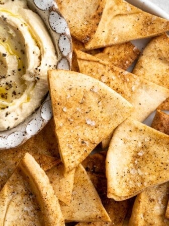 Platter of homemade pita chips with bowl of hummus.