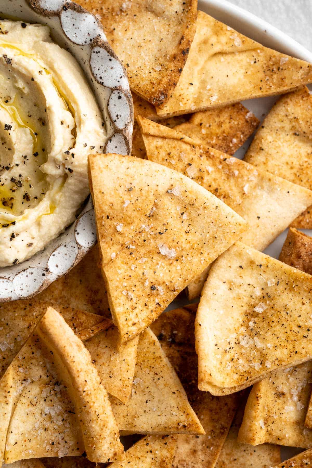 Platter of homemade pita chips with bowl of hummus.
