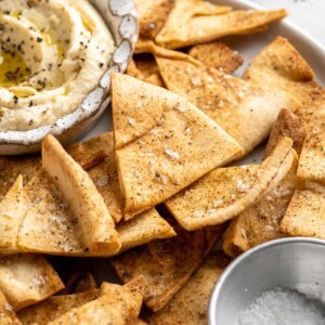 Homemade pita chips with bowl of hummus.