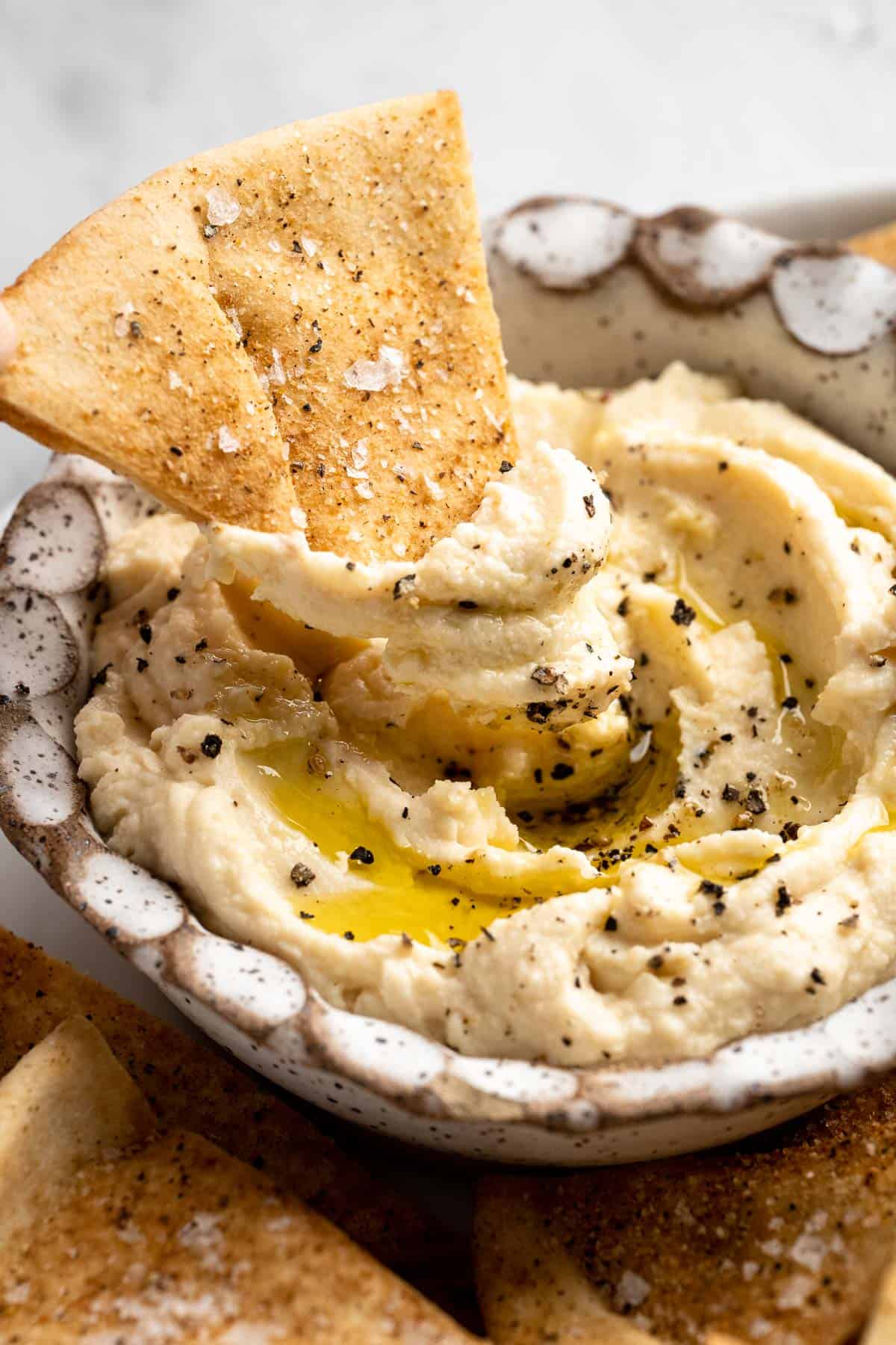 Bowl of hummus with homemade pita chip.