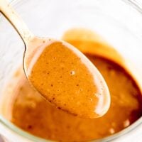 Thai peanut sauce in a gold spoon over a jar.