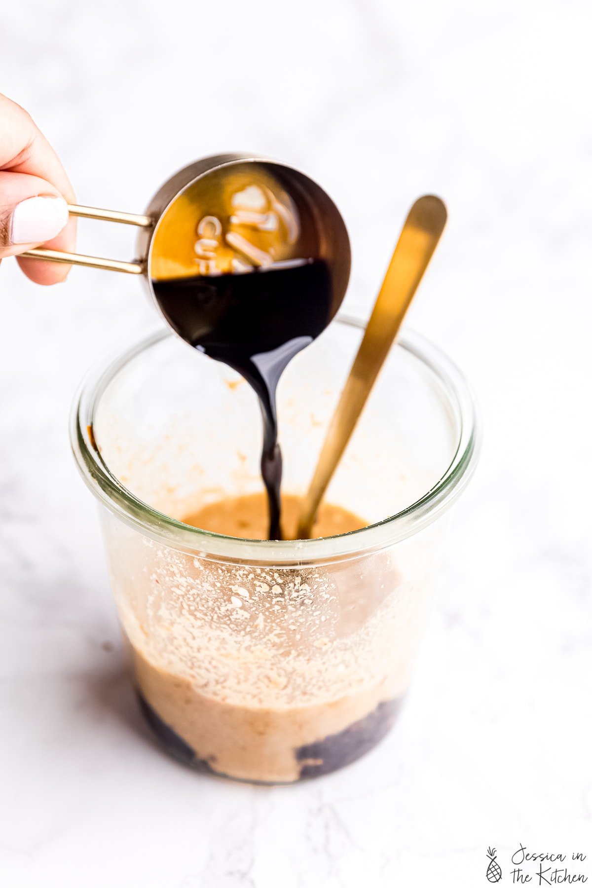 Soy sauce being poured into a jar to make Thai peanut sauce.