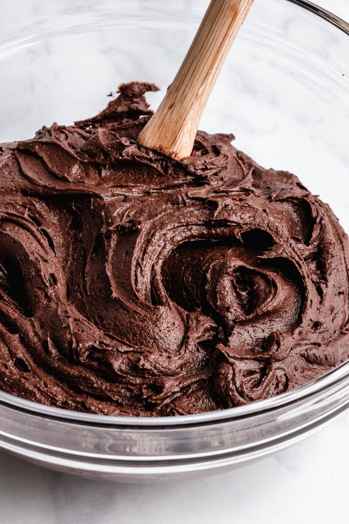 A bowl of vegan chocolate frosting with a spatula in it.
