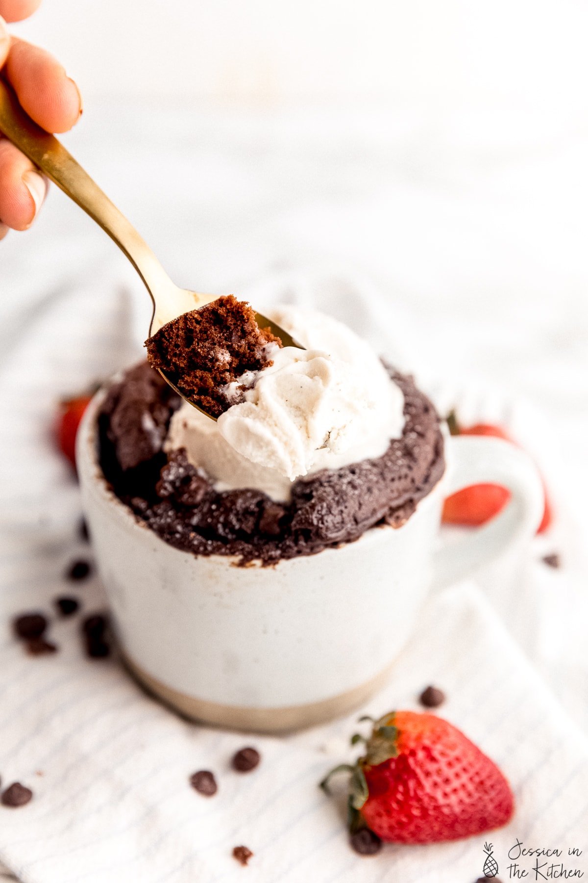 A piece of mug cake on a spoon with some ice cream.