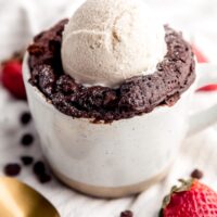 A close up photo of mug cake with a scoop of ice cream on top.