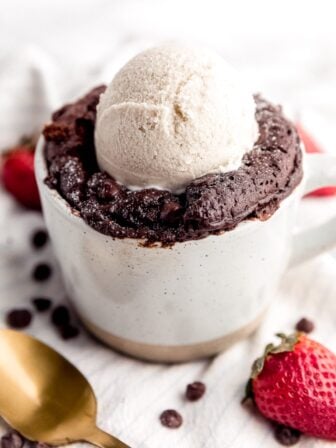 A close up photo of mug cake with a scoop of ice cream on top.