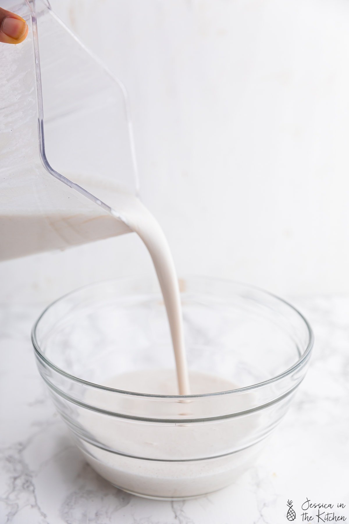 Cashew coconut milk liquid being poured into a bowl.